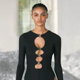 Ein Model trägt ein schwarzes Oberteil mit Cut-outs und Ringen. Dieses auffällige Stück ist ein echter Hingucker.