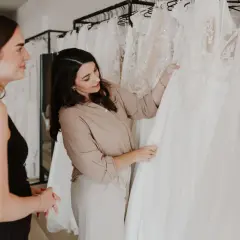Eine Braut und eine Verkäuferin begutachten Brautkleid Schnitte in einem Brautmodengeschäft.