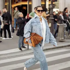 Frau in Jeansjacke und passender Hose, die eine braune Tasche trägt. Perfekt, welche Hose zu Jeansjacke passt!