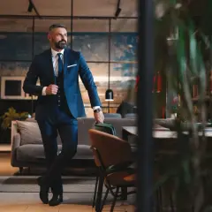 Ein Mann im eleganten dunkelblauen Lounge Suit steht lässig in einem stilvollen Interieur.