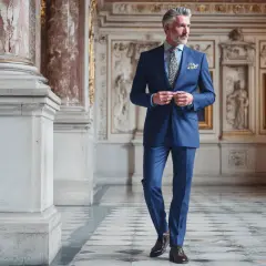 Elegante abiball vater kleidung: Ein Mann im blauen Nadelstreifenanzug, mit gemustertem Einstecktuch und Krawatte, steht in einem prunkvollen Saal.