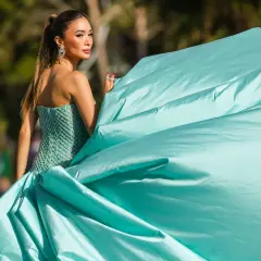Elegante Frau in einem türkisfarbenen Ballkleid, das den **black tie dress code** perfekt verkörpert. Ihr Kleid weht im Wind.