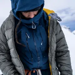 Person in Daunenjacke im Schnee. Tipps zur Daunenjacke Reinigung oder selber waschen.