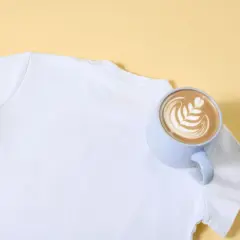 Eine weiße T-Shirt-Schulter mit einer Tasse Latte Art. So lassen sich eingetrocknete Kaffeeflecken entfernen.