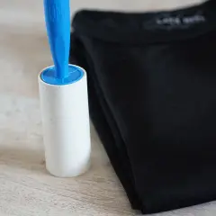 Fusselrolle neben schwarzem T-Shirt. Ein einfaches Hausmittel zum Fussel entfernen.