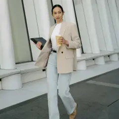 Frau im smart casual Look für Herren Winter, mit Blazer, Jeans und Kaffee.