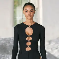 Ein Model trägt ein schwarzes Oberteil mit Cut-outs und Ringen. Dieses auffällige Stück ist ein echter Hingucker.