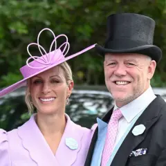 Ein Paar im eleganten Ascot Pferderennen Dresscode: Sie trägt einen lila Hut und Mantel, er einen Zylinder und Anzug.