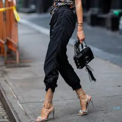 Schwarze Jogginghose kombinieren Herren: lässig mit High Heels und Tasche, ein unerwarteter, aber stylischer Look.