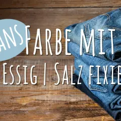 Neue Jeans Farbe mit Essig fixieren: Ein Stapel Jeans auf Holz.
