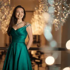 Junge Frau in einem smaragdgrünen Ballkleid mit funkelnden Verzierungen an den Schultern. Perfekt, wenn man sich fragt, was zieht man zum Abiball an.