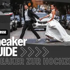 Brautpaar überquert Straße, sie im weißen Kleid, er im Anzug mit Sneaker. Hochzeit mit Sneaker?