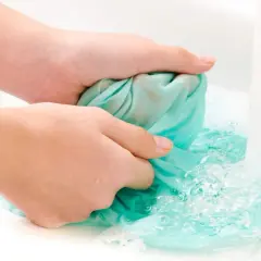 Hände waschen ein türkises Tuch in der Spüle, um Fettspritzer zu entfernen.
