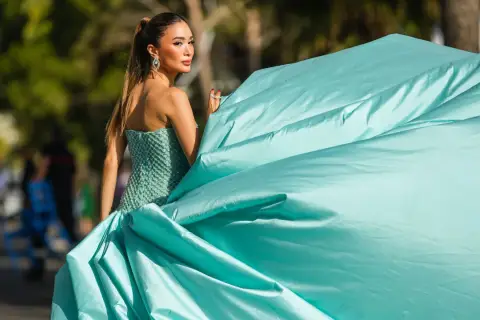 Elegante Frau in einem türkisfarbenen Ballkleid, das den **black tie dress code** perfekt verkörpert. Ihr Kleid weht im Wind.