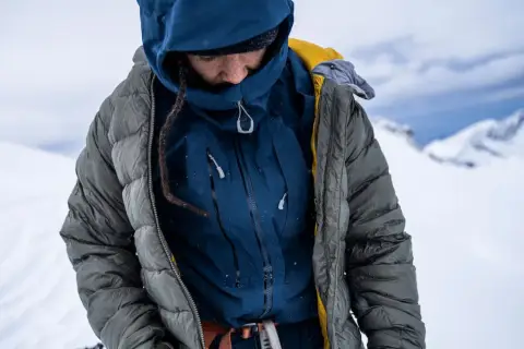 Person in Daunenjacke im Schnee. Tipps zur Daunenjacke Reinigung oder selber waschen.