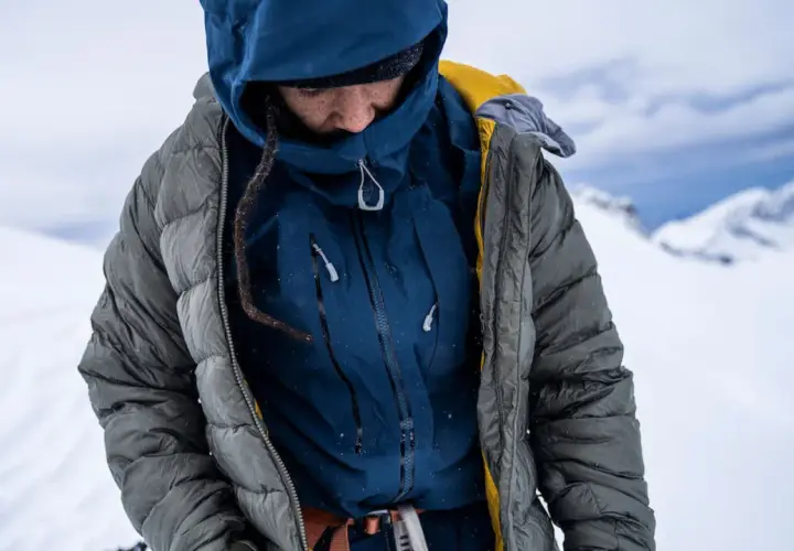 Person in Daunenjacke im Schnee. Tipps zur Daunenjacke Reinigung oder selber waschen.