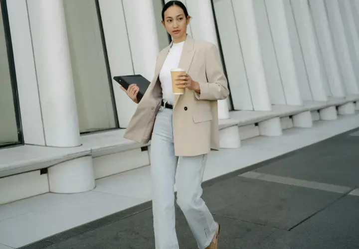 Frau im smart casual Look für Herren Winter, mit Blazer, Jeans und Kaffee.