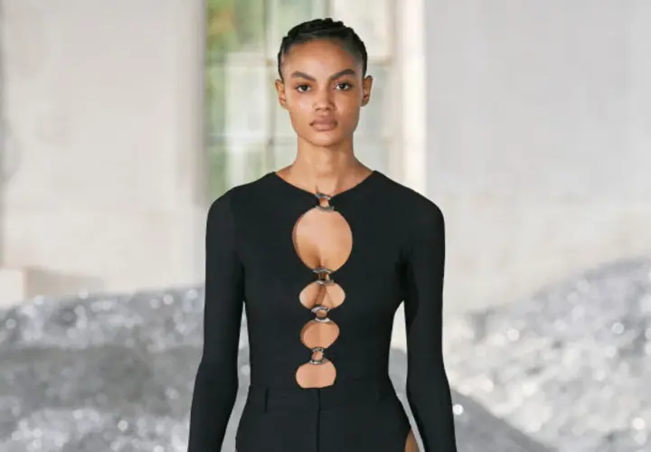 Ein Model trägt ein schwarzes Oberteil mit Cut-outs und Ringen. Dieses auffällige Stück ist ein echter Hingucker.