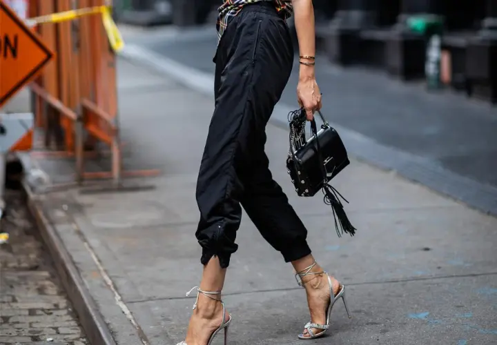 Schwarze Jogginghose kombinieren Herren: lässig mit High Heels und Tasche, ein unerwarteter, aber stylischer Look.