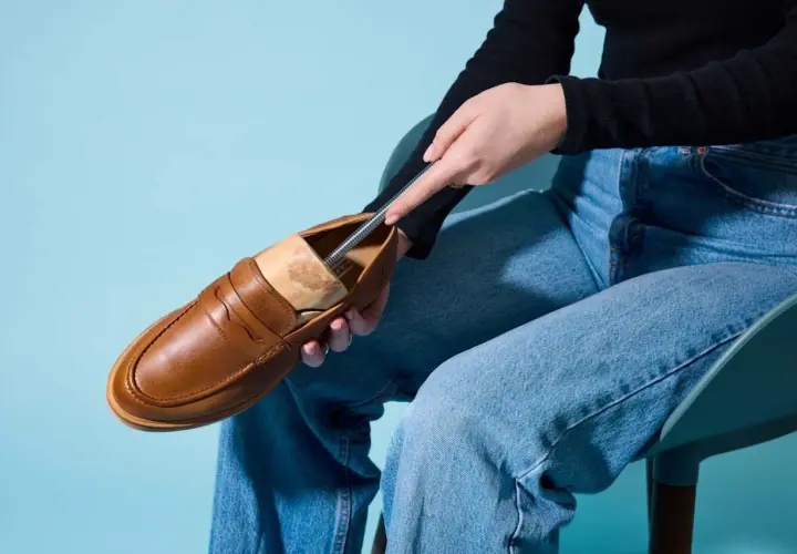 Braune Loafer werden mit einem Schuhspanner geweitet.