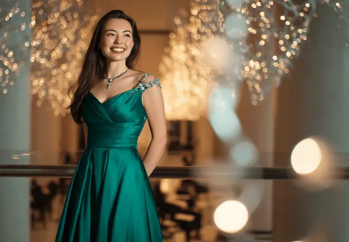 Junge Frau in einem smaragdgrünen Ballkleid mit funkelnden Verzierungen an den Schultern. Perfekt, wenn man sich fragt, was zieht man zum Abiball an.