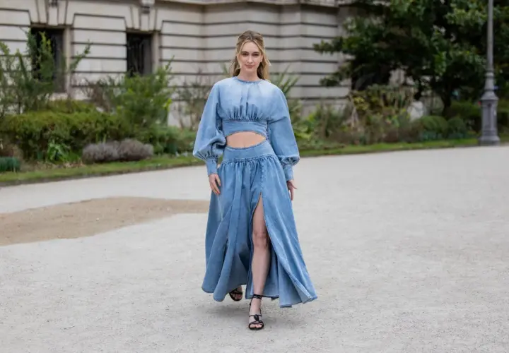 Frau in einem langen Jeanskleid mit Cut-outs und Puffärmeln, dazu schwarze Riemchensandalen. Die perfekte Inspiration, welche Schuhe zum Jeanskleid passen.