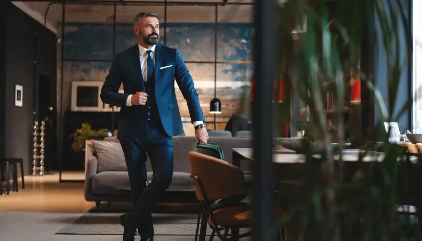Ein Mann im eleganten dunkelblauen Lounge Suit steht lässig in einem stilvollen Interieur.