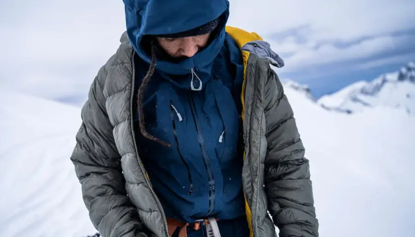 Person in Daunenjacke im Schnee. Tipps zur Daunenjacke Reinigung oder selber waschen.