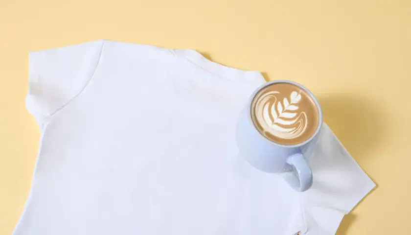 Eine weiße T-Shirt-Schulter mit einer Tasse Latte Art. So lassen sich eingetrocknete Kaffeeflecken entfernen.