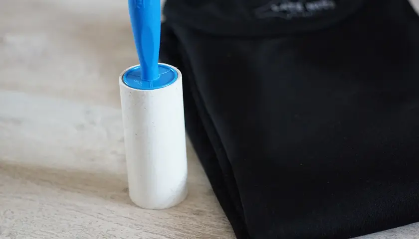 Fusselrolle neben schwarzem T-Shirt. Ein einfaches Hausmittel zum Fussel entfernen.