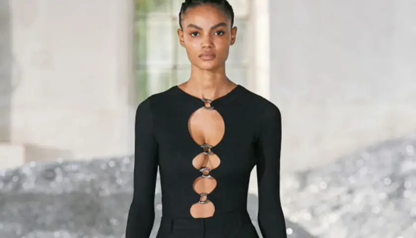 Ein Model trägt ein schwarzes Oberteil mit Cut-outs und Ringen. Dieses auffällige Stück ist ein echter Hingucker.