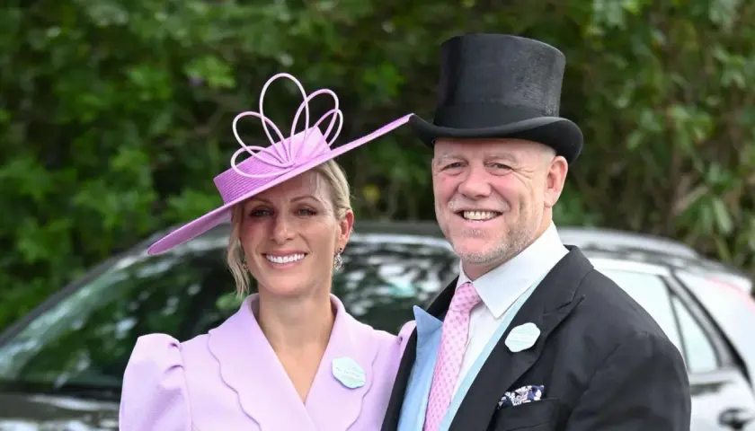 Ein Paar im eleganten Ascot Pferderennen Dresscode: Sie trägt einen lila Hut und Mantel, er einen Zylinder und Anzug.