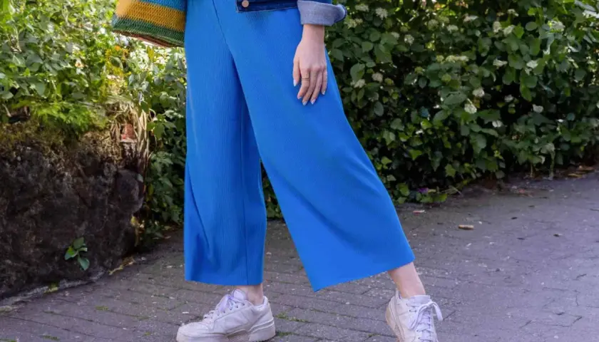 Blaues Culotte-Outfit mit Jeansjacke und bunten Tasche. So lässt sich die Culotte lässig kombinieren.