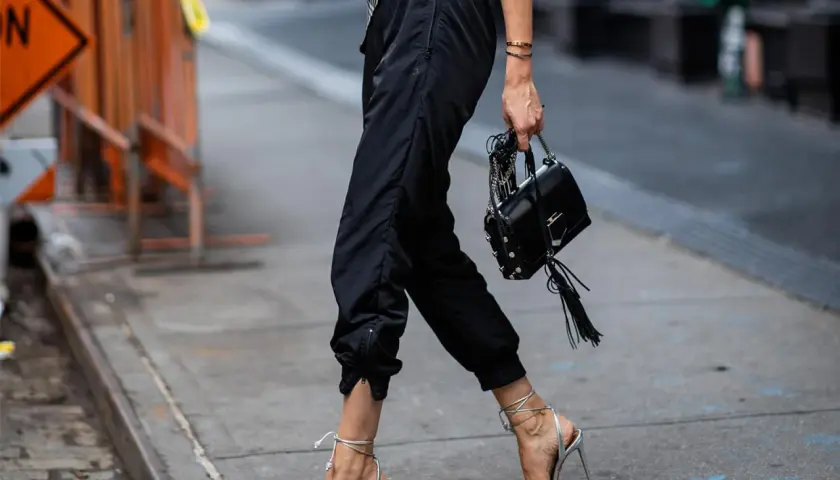 Schwarze Jogginghose kombinieren Herren: lässig mit High Heels und Tasche, ein unerwarteter, aber stylischer Look.