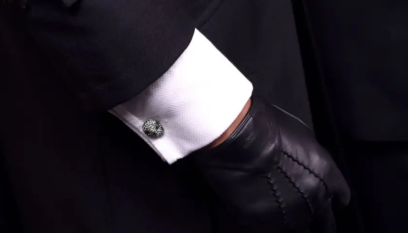 Elegante Manschettenknöpfe zieren das weiße Hemd unter einem schwarzen Anzug. Sie sind kleine Schmuckstücke, die zeigen, was sind Manschetten.