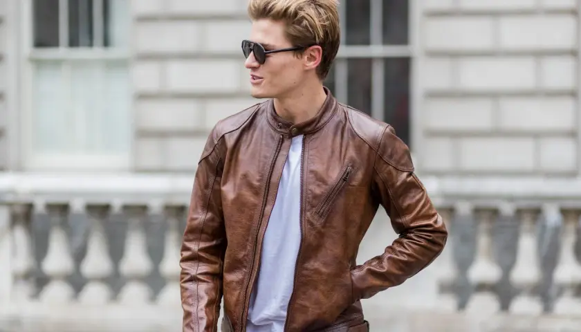 Mann mit brauner Wildlederjacke, die er reinigen möchte. Sonnenbrille und weißes T-Shirt.