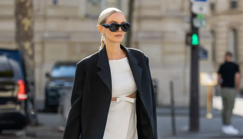 Stylische Frau mit weißem Kleid und schwarzem Blazer. Die Frage, welche Jacke zu langem Kleid passt, wird hier elegant beantwortet.
