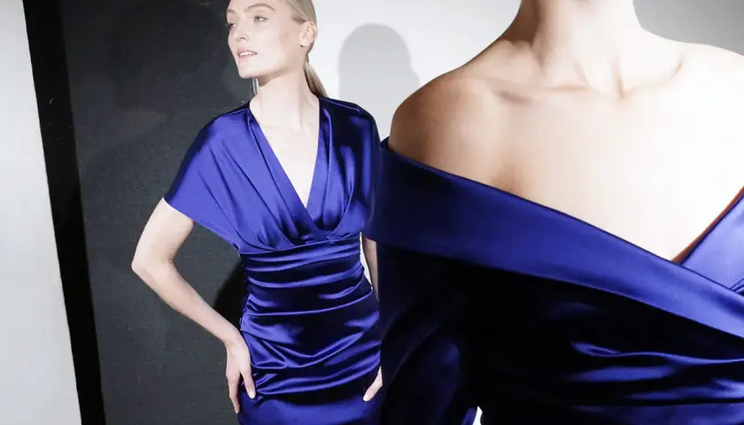 Zwei Frauen in eleganten, königsblauen Satin-Kleidern. Der Dresscode elegant für Frauen wird hier perfekt umgesetzt.