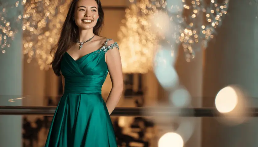 Junge Frau in einem smaragdgrünen Ballkleid mit funkelnden Verzierungen an den Schultern. Perfekt, wenn man sich fragt, was zieht man zum Abiball an.