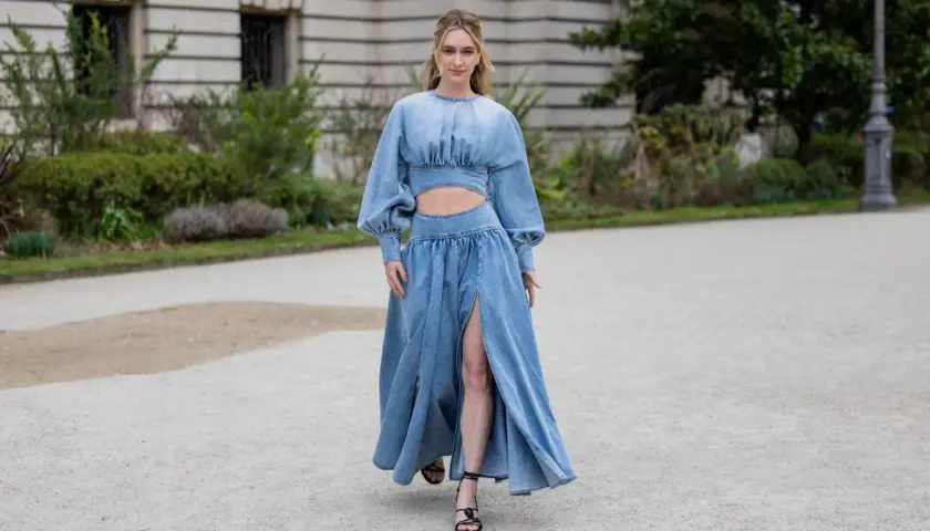 Frau in einem langen Jeanskleid mit Cut-outs und Puffärmeln, dazu schwarze Riemchensandalen. Die perfekte Inspiration, welche Schuhe zum Jeanskleid passen.