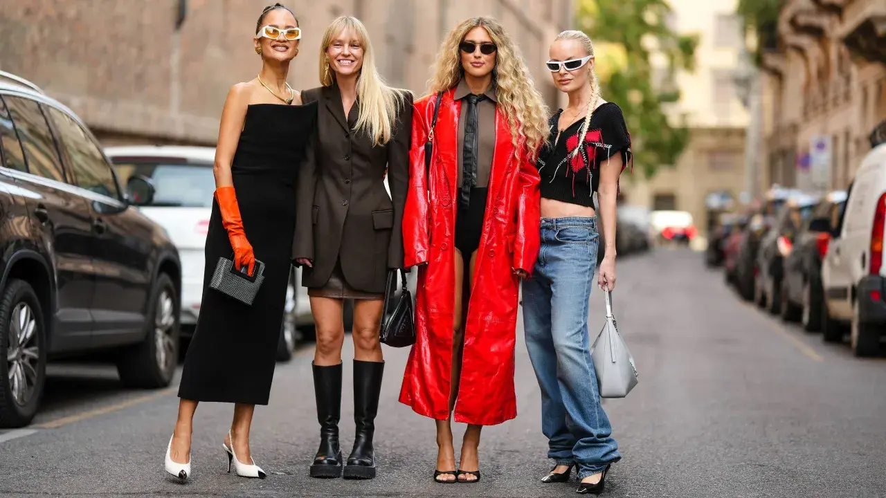 Vier Frauen präsentieren unterschiedliche Dresscodes: von elegantem Schwarz über lässige Jeans bis hin zu auffälligem Rot.