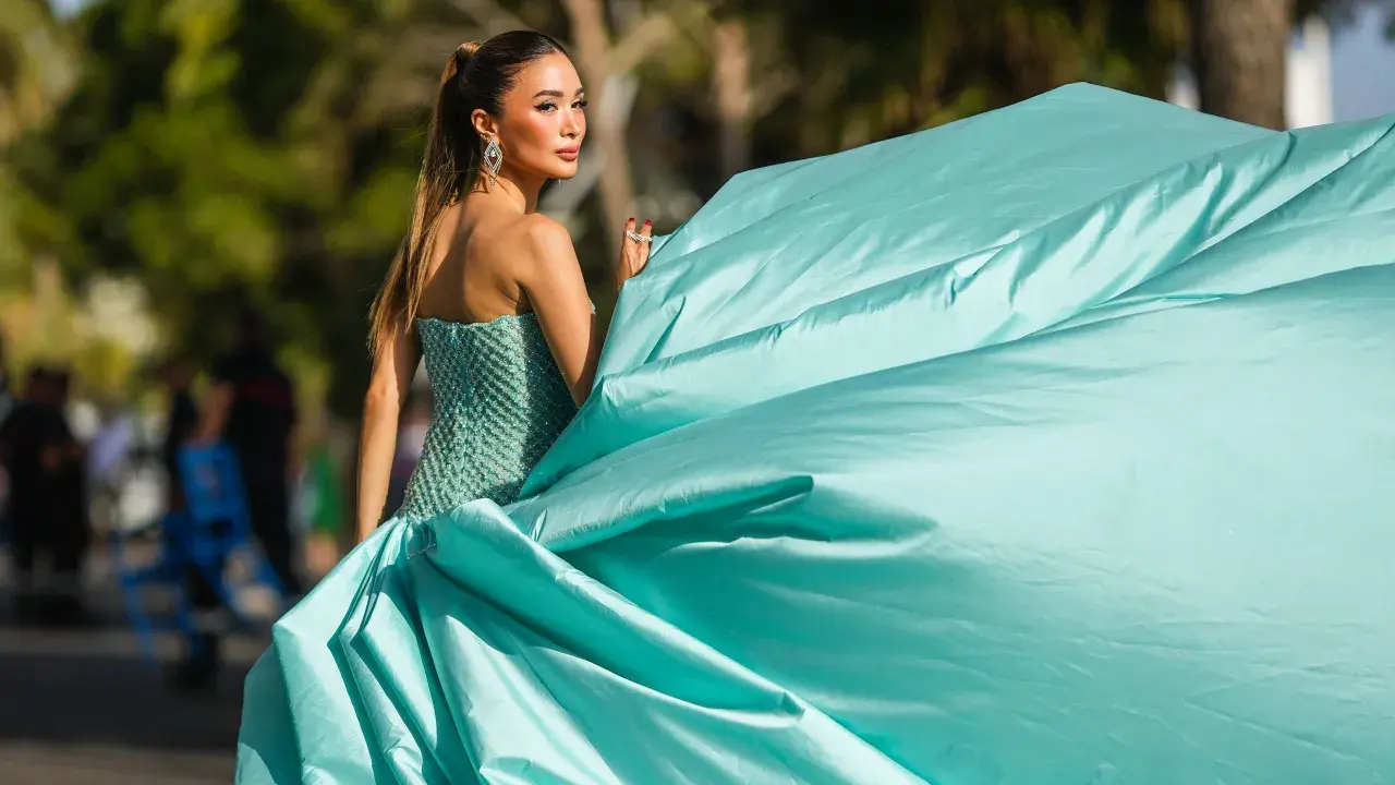 Elegante Frau in einem türkisfarbenen Ballkleid, das den **black tie dress code** perfekt verkörpert. Ihr Kleid weht im Wind.