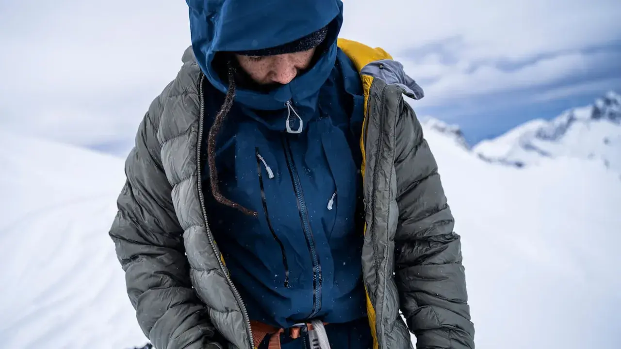 Person in Daunenjacke im Schnee. Tipps zur Daunenjacke Reinigung oder selber waschen.