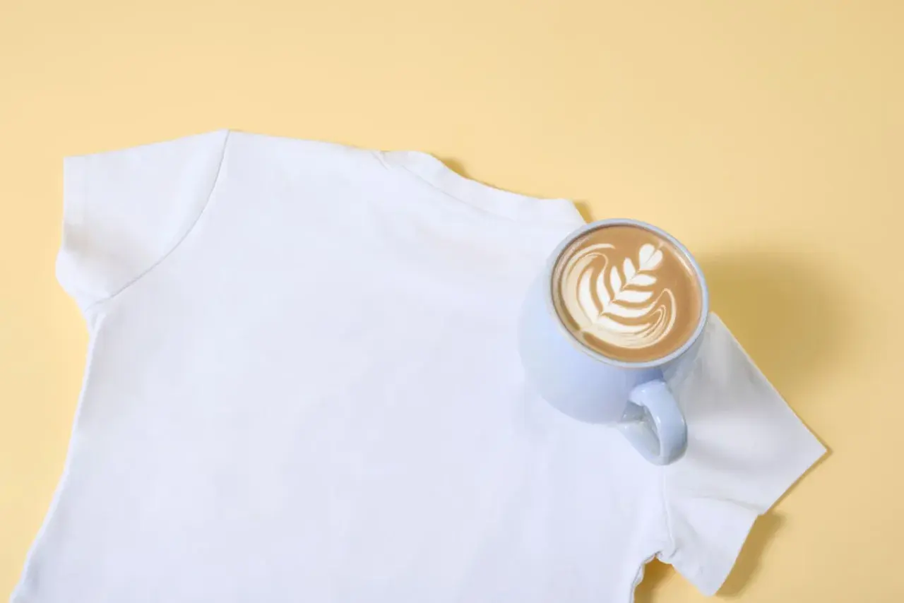 Eine weiße T-Shirt-Schulter mit einer Tasse Latte Art. So lassen sich eingetrocknete Kaffeeflecken entfernen.
