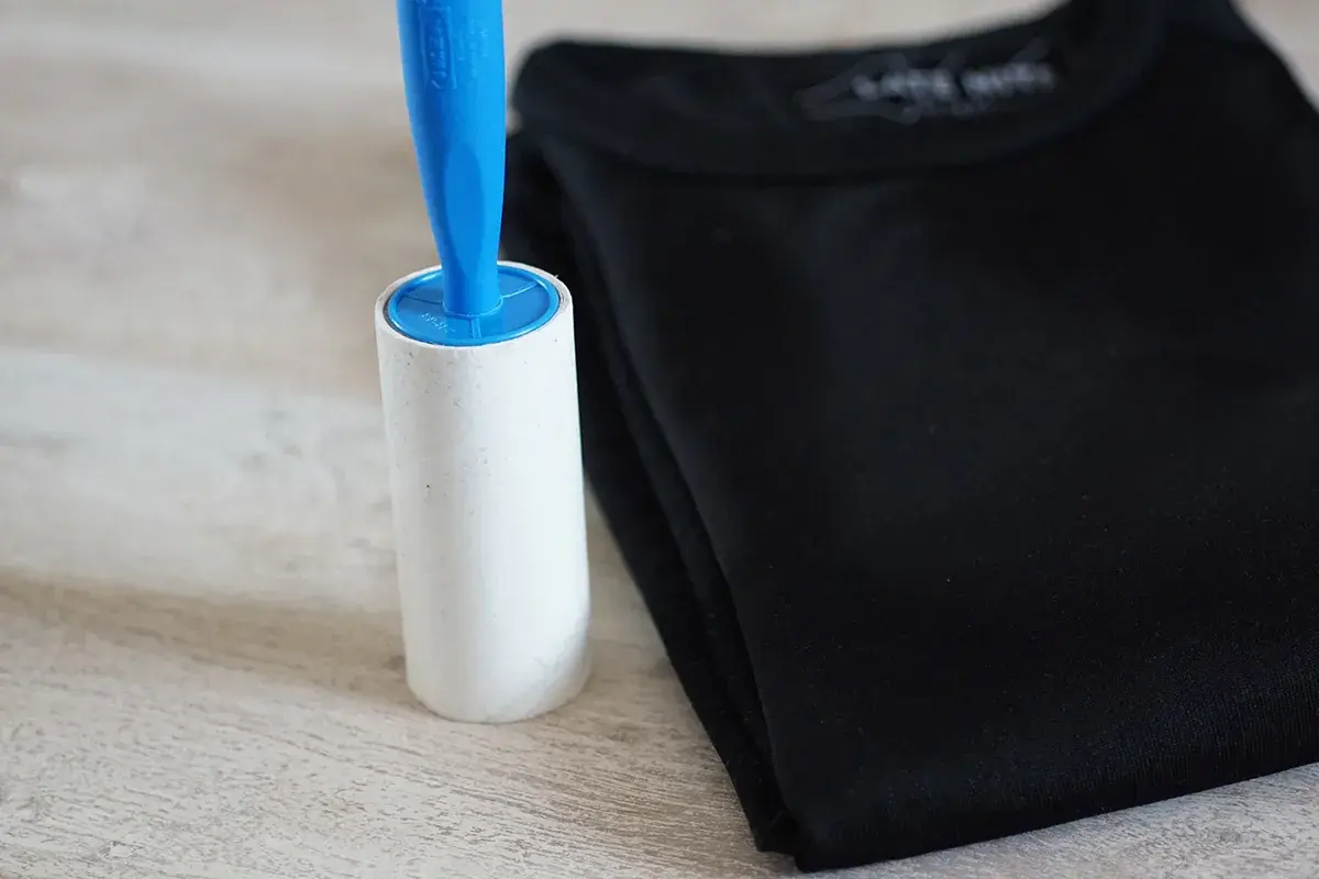 Fusselrolle neben schwarzem T-Shirt. Ein einfaches Hausmittel zum Fussel entfernen.