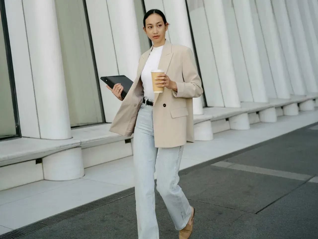 Frau im smart casual Look für Herren Winter, mit Blazer, Jeans und Kaffee.