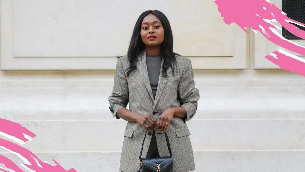 Eine Frau in einem karierten Blazer und dunklem Oberteil verkörpert smart business casual. Sie trägt eine schwarze Handtasche.