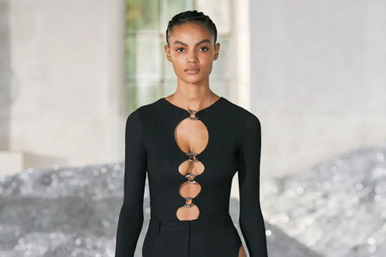 Ein Model trägt ein schwarzes Oberteil mit Cut-outs und Ringen. Dieses auffällige Stück ist ein echter Hingucker.