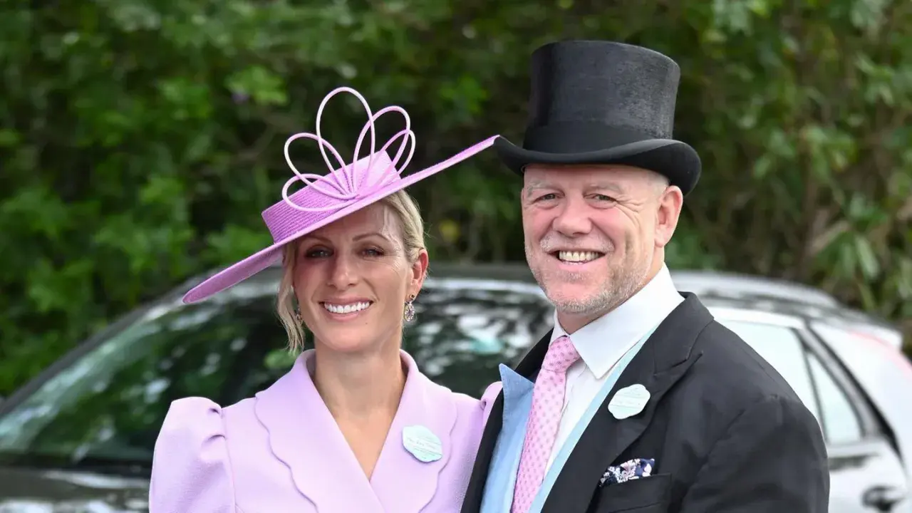 Ein Paar im eleganten Ascot Pferderennen Dresscode: Sie trägt einen lila Hut und Mantel, er einen Zylinder und Anzug.