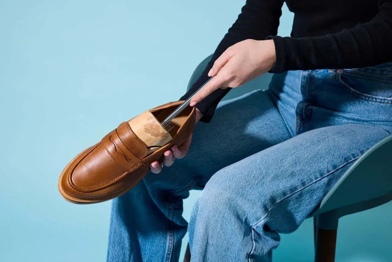 Braune Loafer werden mit einem Schuhspanner geweitet.